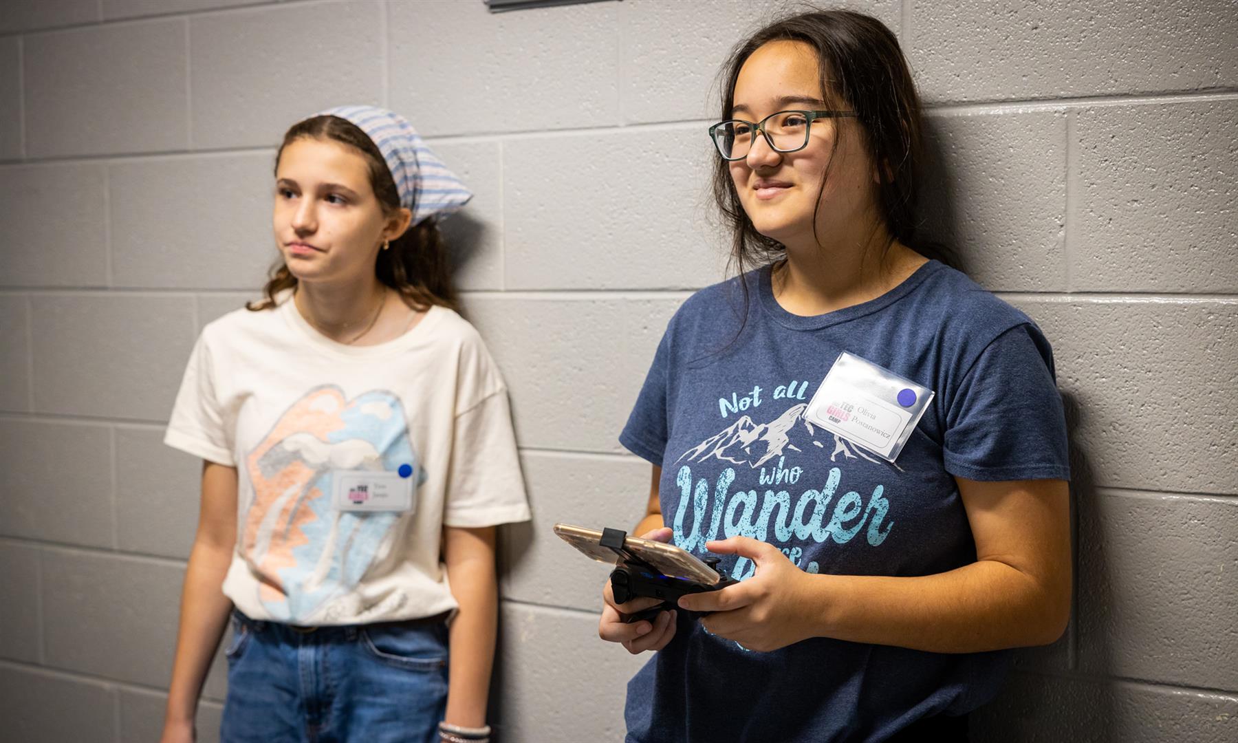 Two girls fly a drone in a hallway